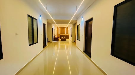 A hotel hallway with a polished floor, framed artwork on the walls, and a seating area in the distance.