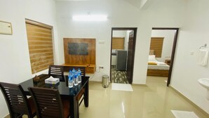 A hotel room with a dining area, a bed, a bathroom, and a view of the outside. - Adam Homes (Aluva)