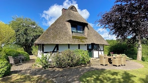 A traditional thatched-roof house with a paved pathway leading to a seating area. - Uniquely charming thatched cottage with 900 square meters of land and a view of the Baltic Sea Pure nature (Damp)