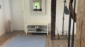 A room with a wooden floor, a blue rug, a white bench, a mirror, and a wooden beam structure. - Uniquely charming thatched cottage with 900 square meters of land and a view of the Baltic Sea Pure nature (Damp)
