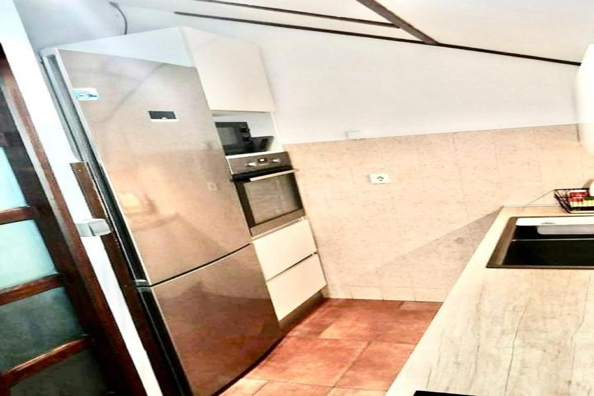 Eine kleine Küche mit Kühlschrank, Backofen und Spüle.