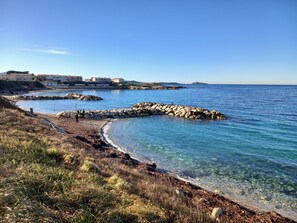 A coastal scene with clear blue water, rocky breakwaters, and a grassy shoreline. - Paradise is here (Six-Fours-les-Plages)