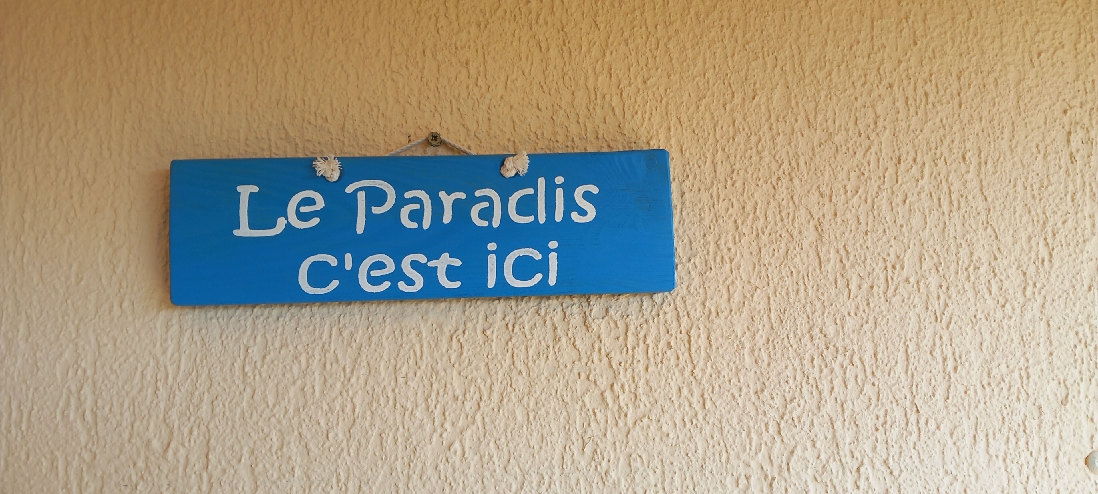 A blue sign with white text on a beige wall.