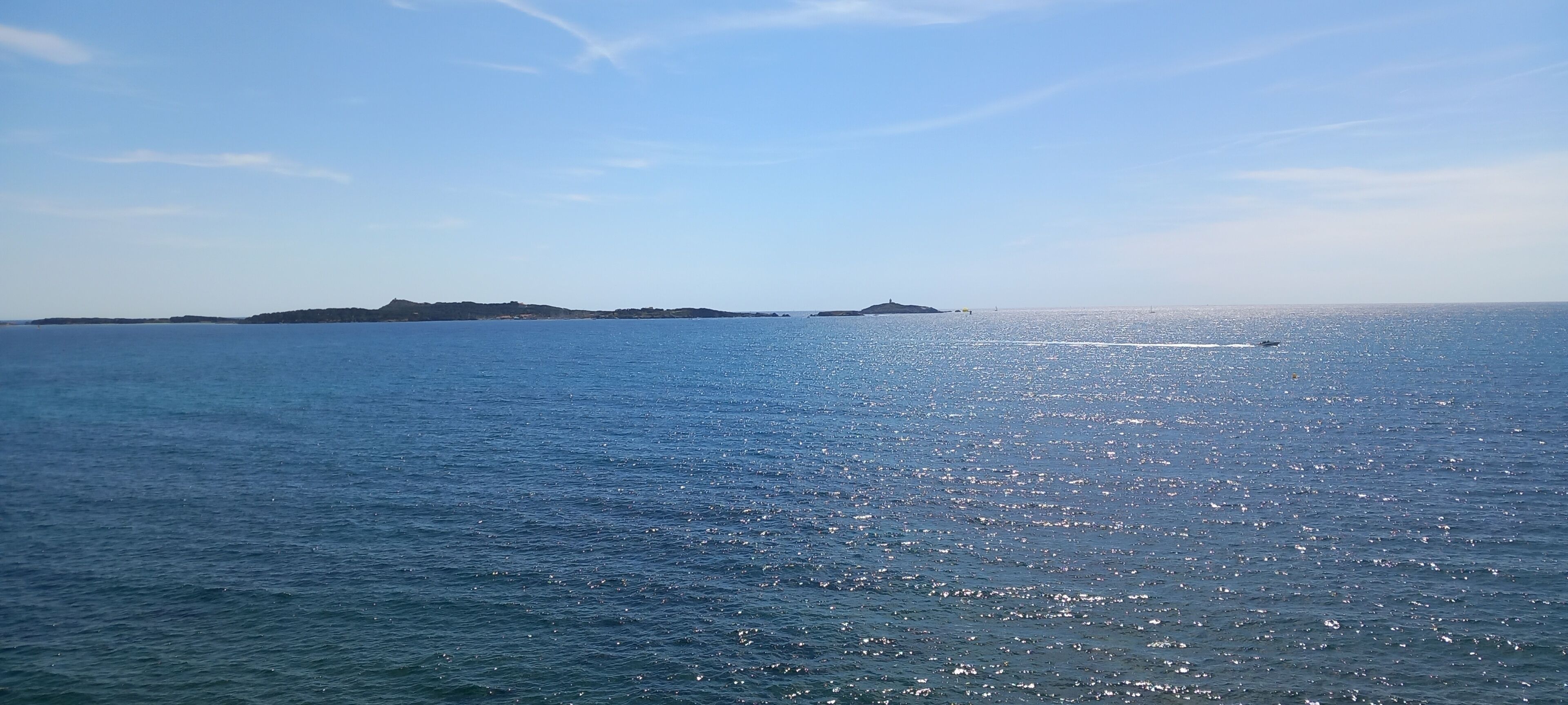 A calm sea with distant landforms under a clear sky.