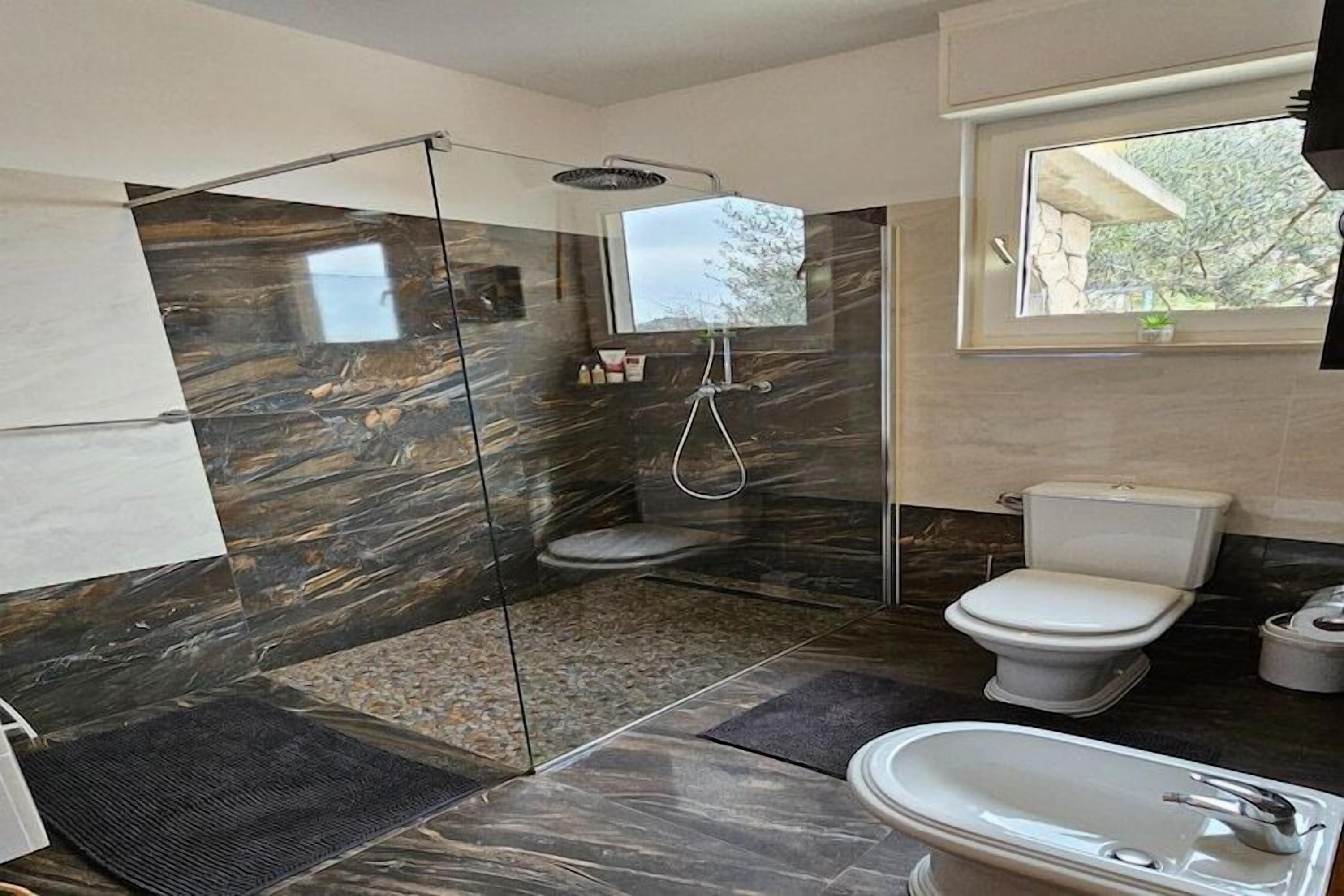 Une salle de bain moderne dotée d’une douche à parois de verre, de toilettes et d’un lavabo.