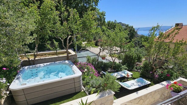 Un bain à remous entouré d’une végétation luxuriante, avec vue sur la mer.