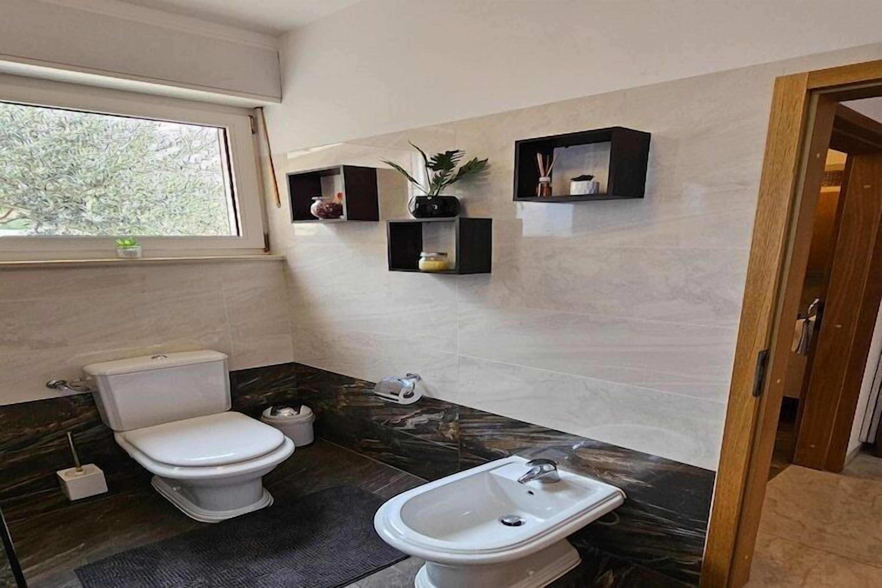 A modern bathroom with a toilet, bidet, and marble countertop.