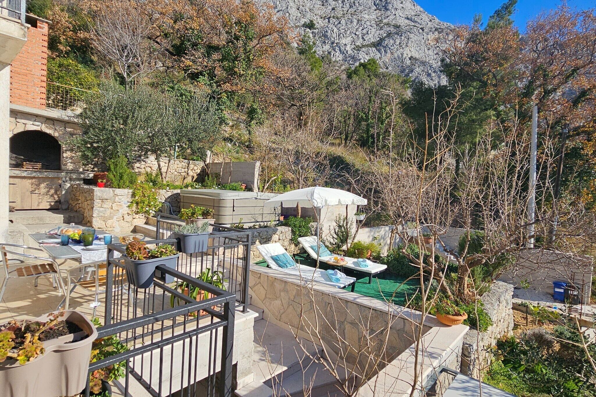 An outdoor patio with lounge chairs, a stone wall, and a view of a mountainous landscape.