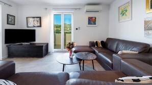 Una sala de estar moderna con un televisor de pantalla plana, sofás de cuero, una mesa de centro y obras de arte en las paredes.