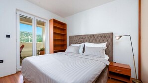 Un dormitorio con cama, mesita de noche, lámpara de pie, puerta corrediza de vidrio y estantería de madera.