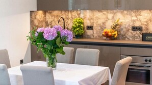 Una cocina moderna con salpicadero de mármol, una mesa de comedor con sillas y un jarrón con flores.