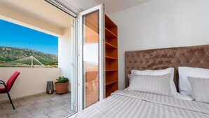 Un dormitorio con cama, puerta corrediza a un balcón y vista a un puente.