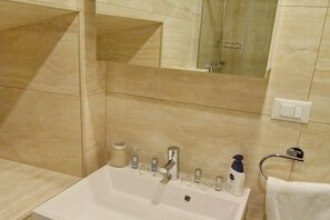 A bathroom with a white sink, a mirror, and a shower area.
