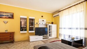 A living room with a TV, sofa, and a small table.