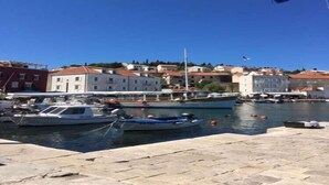 Un puerto deportivo con barcos amarrados, una bandera y edificios al fondo.