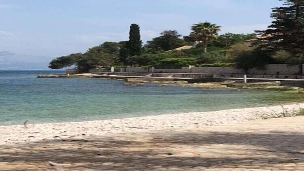 Un camino costero con pavimento de piedra que conduce a una playa de arena.