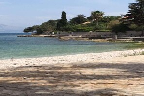 A coastal walkway with a stone pavement leading to a sandy beach.