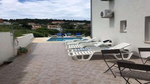 Una terraza en la azotea con tumbonas, piscina y vistas del entorno.