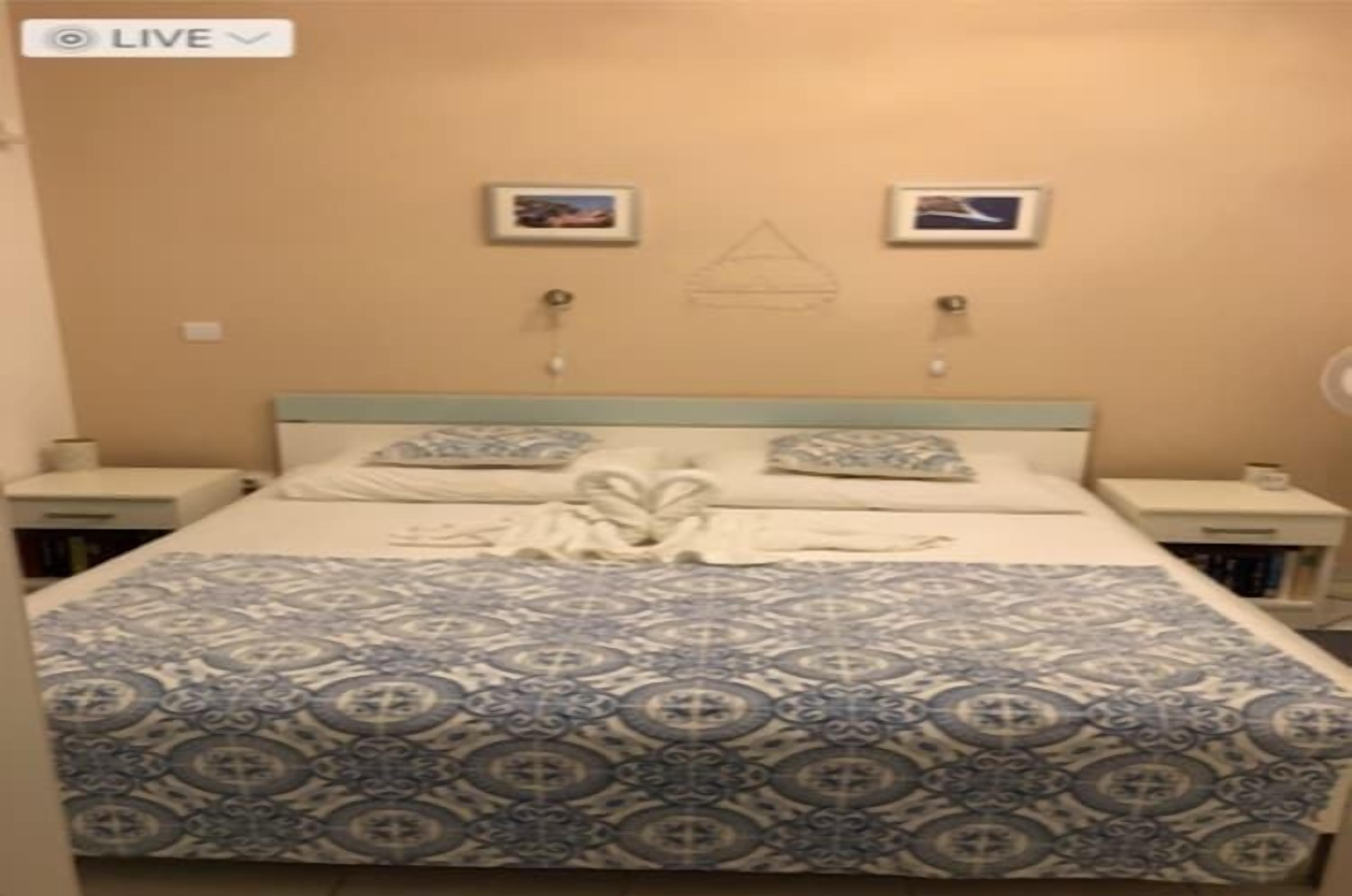 Een hotelkamer met een bed, twee nachtkastjes en een muur met twee ingelijste foto's.