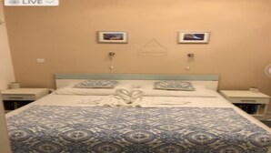Una habitación de hotel con una cama, dos mesitas de noche y una pared decorada con dos cuadros.