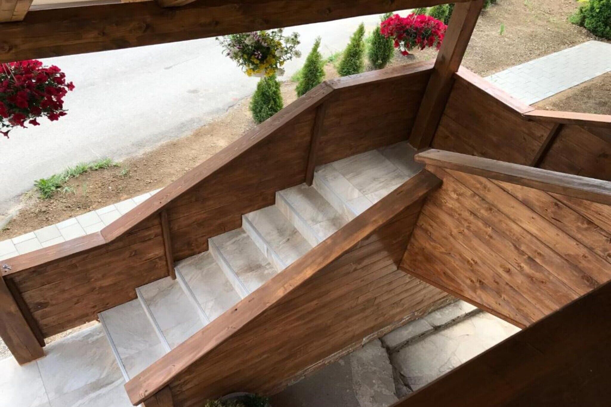 Uma escadaria de madeira com vista para um jardim e uma estrada.