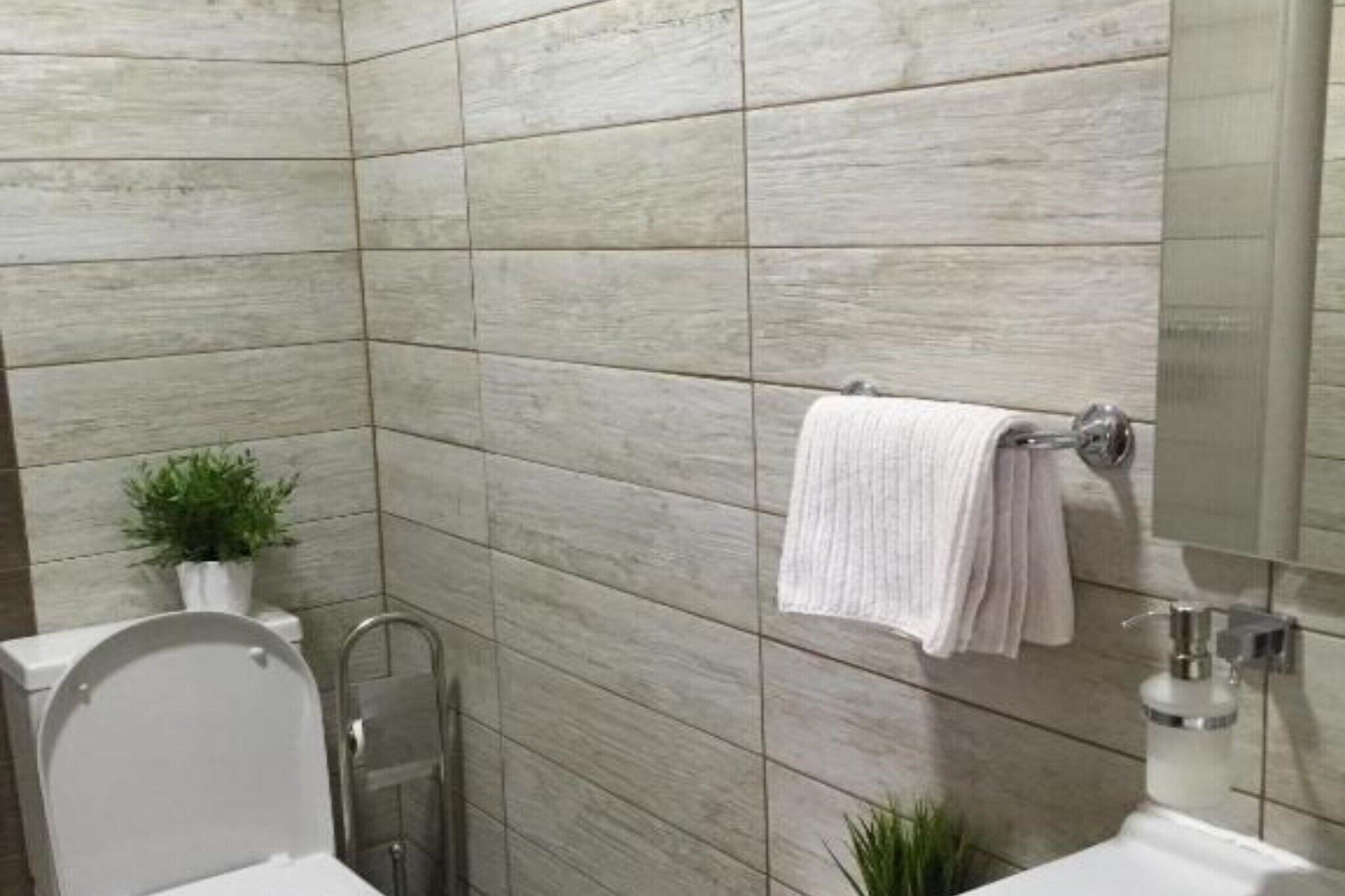 A bathroom with a modern design, featuring a toilet, a shower, and a sink.