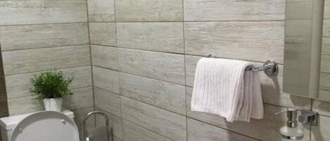 A bathroom with a modern design, featuring a toilet, a shower, and a sink.