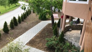 Een tuinomgeving met een bestraat pad, netjes gesnoeide struiken en een stenen border.