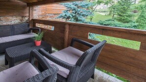 An outdoor patio with wicker furniture and a view of a garden.
