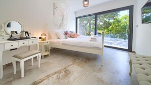 A bedroom with a white bed, a desk, a bench, and a large window offering a view of greenery. - Wellness Villa- Four Bedroom Villa with Swimming pool (Grizane)