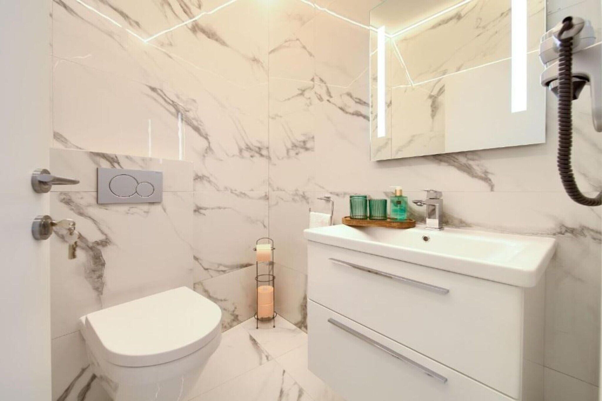 A modern bathroom with a toilet, a sink, and a mirror.