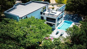 A modern two-story house with a swimming pool, surrounded by lush greenery. - Wellness Villa- Four Bedroom Villa with Swimming pool (Grizane)