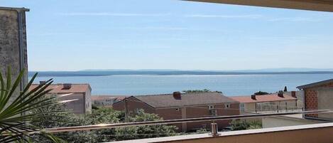 A balcony with a view of a body of water and buildings in the distance.