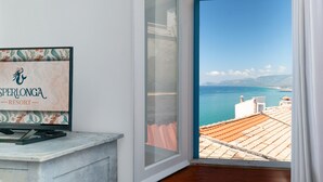 A room with a view of the sea and mountains, a framed sign on the wall, and a window with curtains. - Casa Dafne Sperlongaresort (Sperlonga)