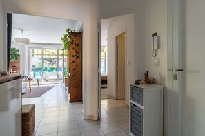 A modern interior with a kitchen, dining area, and a view through a glass door to an outdoor space.
