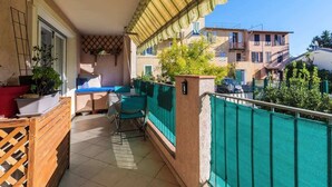 A balcony with a green mesh fence, a wooden table, and chairs. - Large 2 room apartment and beautiful terrace (Niza)