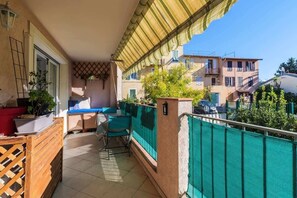 A balcony with a green mesh fence, a wooden table, and chairs.