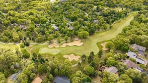 An aerial view of a residential area with a golf course, houses, and dense greenery. - Spacious Lake Arrowhead Golf Course Retreat (Nekoosa)