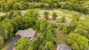 An aerial view of a golf course with sand bunkers, surrounded by dense trees and a few buildings. - Spacious Lake Arrowhead Golf Course Retreat (Nekoosa)