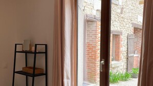 Une pièce dotée d’une porte-fenêtre coulissante donnant sur un espace extérieur avec des murs en briques et un chemin de gravier.