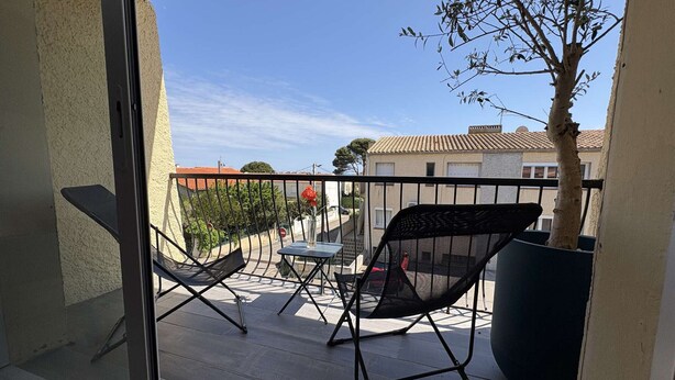 Un balcone con due sedie, un tavolo e una pianta in vaso.