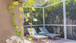 A poolside area with lounge chairs and a small table, surrounded by potted plants and a clear view of trees. - Poolside Palms Getaway- Near Tampa Brandon Valrico (Valrico)