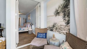 Une chambre à coucher comprenant un lit, une chaise, un tableau accroché au mur et une porte donnant sur une autre pièce.
