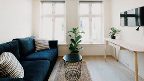 Un saló modern amb un sofà blau fosc, una taula auxiliar rodona negra i una planta en test.