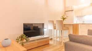 A modern living room with a flat-screen TV, a grey sofa, and a wooden coffee table.