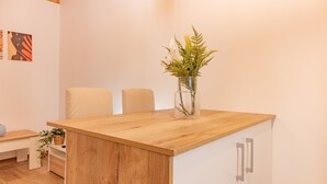 A wooden table with a vase of flowers, two chairs, a bench, and a basket with a plant.