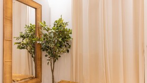 Habitació amb mirall, una planta i prestatgeries de bambú.