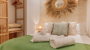 Un dormitorio ordenado con cama, almohadas, un espejo colgado y un armario de madera.