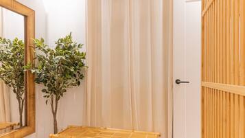 Un baño con puerta de madera, un espejo y una pequeña mesa con una planta.