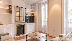 Una sala de estar con chimenea, un sofá, una mesita de centro y vistas al exterior a través de un ventanal grande.
